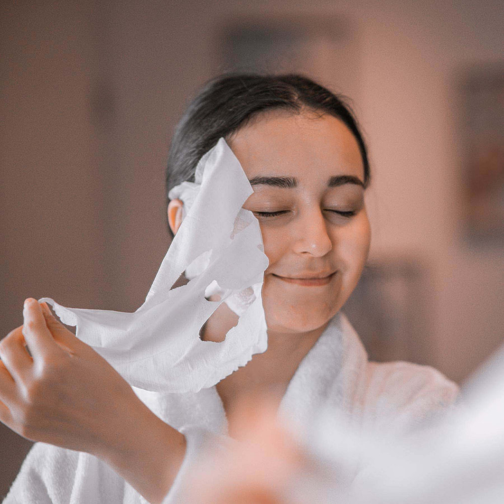 Frau nimmt sich Vliesmaske ab
